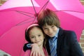 Loving siblings under pink umbrella