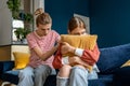 Loving supportive mother sitting on sofa with upset teenage girl, supporting depressed teen