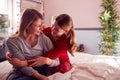 Loving Teenage Daughter Wearing Pyjamas Hugging Mother In Bedroom