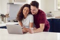 Loving Transgender Couple At Home Together Looking At Laptop On Kitchen Counter