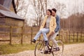 Loving Transgender Couple With Woman Riding On Handlebars Of Bike In Autumn Or Winter Countryside