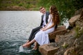 Loving wedding couple sitting and kissing near water Royalty Free Stock Photo