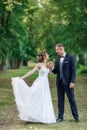 Loving wedding couple standing outside in park. Young man groom holding hand of bride, dancing, looking at each other. Royalty Free Stock Photo