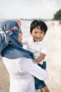 Loving young asian mother holding her son smiling and laughing at the beach Royalty Free Stock Photo