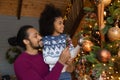 Happy biracial dad and small daughter decorate fir-tree