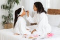 Loving young black mother doing makeup to her little daughter at home Royalty Free Stock Photo
