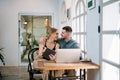 Loving young caucasian couple using laptop together while sitting in chair at home. Concept of couples sharing one idea together Royalty Free Stock Photo