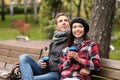 Loving young couple with coffee sitting on wooden bench in autumn park Royalty Free Stock Photo