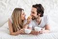 Loving young couple eating breakfast and drinking coffee in bed at home. Lazy romantic morning concept Royalty Free Stock Photo