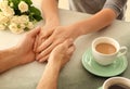 Loving young couple holding hands on light table, closeup Royalty Free Stock Photo