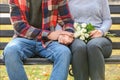 Loving young couple holding hands while sitting on wooden bench outdoors Royalty Free Stock Photo