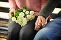 Loving young couple holding hands while sitting on wooden bench outdoors Royalty Free Stock Photo