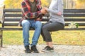 Loving young couple holding hands while sitting on wooden bench outdoors Royalty Free Stock Photo