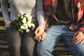 Loving young couple holding hands while sitting on wooden bench outdoors Royalty Free Stock Photo