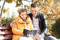 Loving young couple reading book in autumn park Royalty Free Stock Photo