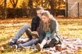 Loving young couple reading book on plaid in autumn park Royalty Free Stock Photo