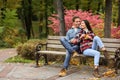 Loving young couple sitting on wooden bench in autumn park Royalty Free Stock Photo