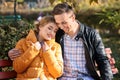 Loving young couple sitting on wooden bench in autumn park Royalty Free Stock Photo