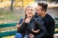 Loving young couple sitting on wooden bench in autumn park Royalty Free Stock Photo