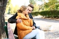 Loving young couple sitting on wooden bench in autumn park Royalty Free Stock Photo