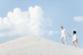 Loving a young couple on vacation, enjoying a walk on the sunny sandy beach. Man and girl in light summer clothes. Royalty Free Stock Photo