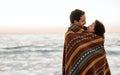 Loving young couple wrapped in a blanket at the beach Royalty Free Stock Photo