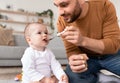 Loving Young Father Spoon Feeding His Little Baby Sitting Indoors Royalty Free Stock Photo