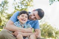 Loving Young Father Tickling Son in the Park.