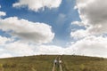 Loving young happy couple running on a green meadow with blue cloudy sky on the background Royalty Free Stock Photo