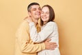 Loving young man and woman couple standing together  over beige background hugging smiling happily expressing love and Royalty Free Stock Photo