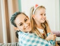 Loving young mother laughing hugging smiling cute cheerful daughter