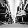 Low agle view of passenegers commercial airplane aisle with passenegers sitting on their seats while flying. Black and