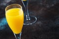 Low alcohol cocktail mimosa with orange juice and cold dry champagne or sparkling wine in glasses, blue background with flowers,