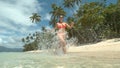 LOW ANGLE: Active young woman runs in her bikini along sandy beach in summer. Royalty Free Stock Photo