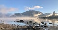 Low-angle Alaskan panorama with the lake full of stones and fog over, mountains and sky background Royalty Free Stock Photo