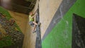 LOW ANGLE: Athletic man climbs up difficult climbing route at bouldering gym.