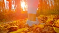 LOW ANGLE: Athletic woman kicks up fallen leaves while jogging in the forest.