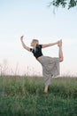 Low angle of balancing on one foot young blond woman exercising in a field