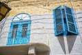 Low angle of a balcony with blue window shutters on brick wall.