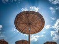 Low angle of a beach straw umbrella against a blue sky with clouds. Royalty Free Stock Photo