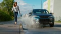 LOW ANGLE: Businesswoman walking along sidewalk gets splashed by careless driver Royalty Free Stock Photo