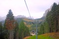 Low-angle of cableways in the Dolomites, with green trees and yellowing grass on both sides Royalty Free Stock Photo