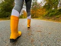 CLOSE UP: Female traveler wears rubber boots while walking down a forest route