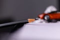 Low angle close up shot of a pencil nib placed on spiral notebook and toy car blurred in the background -Dreams concept Royalty Free Stock Photo