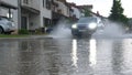 LOW ANGLE: SUV driving through the flooded suburbia on a rainy spring day.