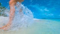 CLOSE UP: Unrecognizable woman splashes water as she runs along tropical beach. Royalty Free Stock Photo