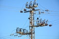 Low angle close-up view of the top part of an electricity distribution pylon and power lines under blue sky Royalty Free Stock Photo