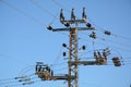 Low angle close-up view of the top part of an electricity distribution pylon and power lines under blue sky Royalty Free Stock Photo