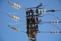 Low angle close-up view of the top part of an electricity distribution pylon and power lines under blue sky Royalty Free Stock Photo