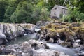 Low-angle closeup of Cenarth falls with a stone house and green trees background, Wales Royalty Free Stock Photo